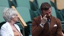<p>Mantan pesepakbola David Beckham dan ibunya Sandra Georgina West bereaksi dari Royal Box di Centre Court selama pertandingan tenis perempat final tunggal putri antara Simona Halep dari Rumania dan pemain AS Amanda Anisimova pada hari kesepuluh Kejuaraan Wimbledon 2022 di The Klub Tenis All England di Wimbledon, London (6/7/2022). (AFP/Adrian Dennis)</p>