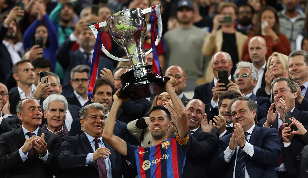 Selebrasi gelandang dan kapten Barcelona, Sergio Busquets dengan mengangkat trofi Copa del Rey 2022/2023 setelah mengalahkan Real Sociedad pada laga final di Camp Nou Stadium, Barcelona (20/5/2023). Ingin bereuni dengan Lionel Messi di Inter Miami menjadi alasan utama Sergio Busquets menolak tawaran beberapa klub Arab Saudi usai resmi meninggalkan Barcelona pada akhir musim 2022/2023 setelah 15 tahun membela Blaugrana. (AFP/Lluis Gene)