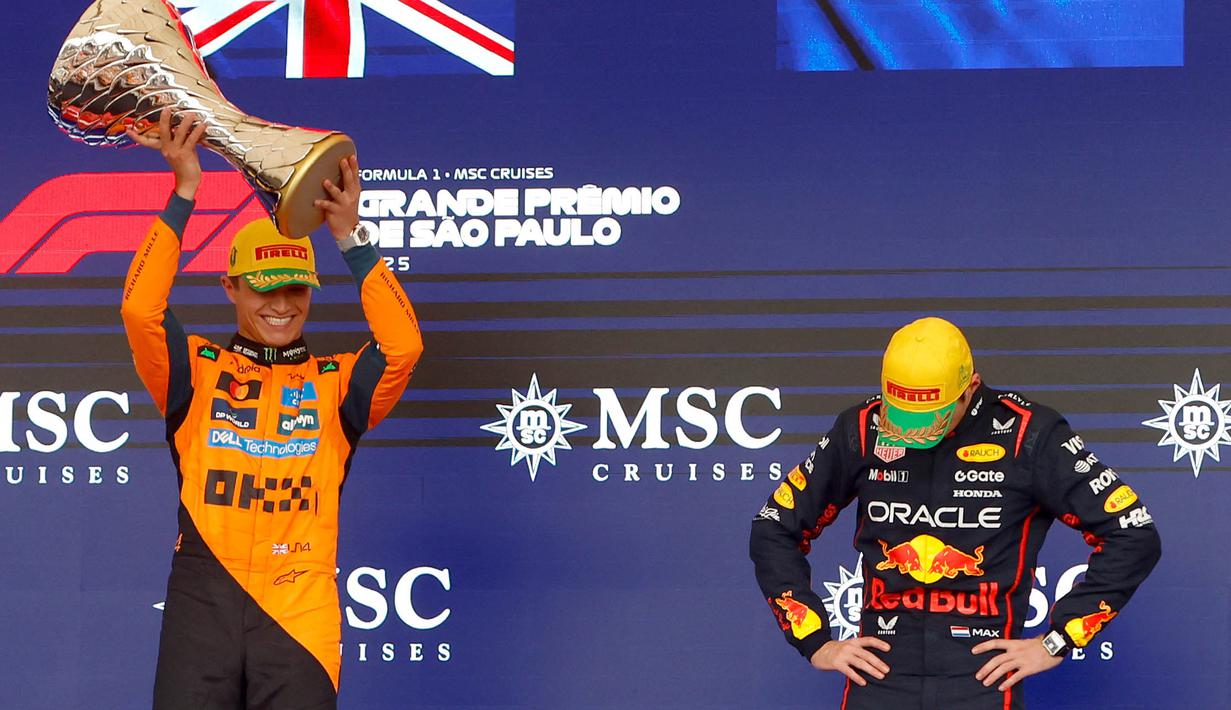 Pembalap Red Bull Racing, Max Verstappen (kanan) tertunduk saat pembalap McLaren, Lando Norrris mengangkat trofi kemenangan dalam Formula 1 GP Sao Paulo di Interlagos, Sao Paulo, Brasil, Minggu (09/11/2025). (AFP/Miguel Schincariol)