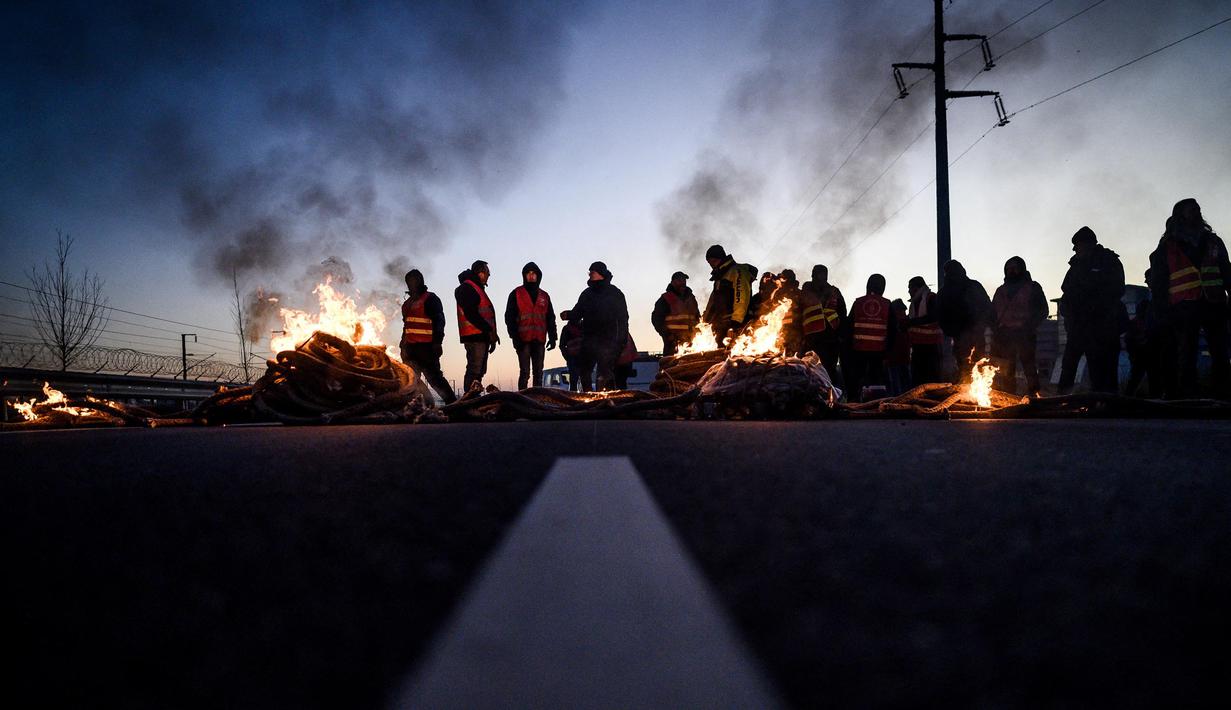 Puluhan anggota serikat pekerja memblokir jalan di depan kilang Total Energies dalam sebuah aksi yang diserukan oleh serikat pekerja Konfederasi Umum Buruh Prancis (CGT) untuk menentang perombakan dana pensiun yang sangat tidak populer di Donges, Prancis Barat, Rabu (8/2/2023). Prancis bersiap menghadapi pemogokan baru dan demonstrasi massal menentang proposal Presiden Prancis untuk mereformasi pensiun Prancis, termasuk menaikkan usia pensiun dari 62 menjadi 64 tahun. (LOIC VENANCE/AFP)