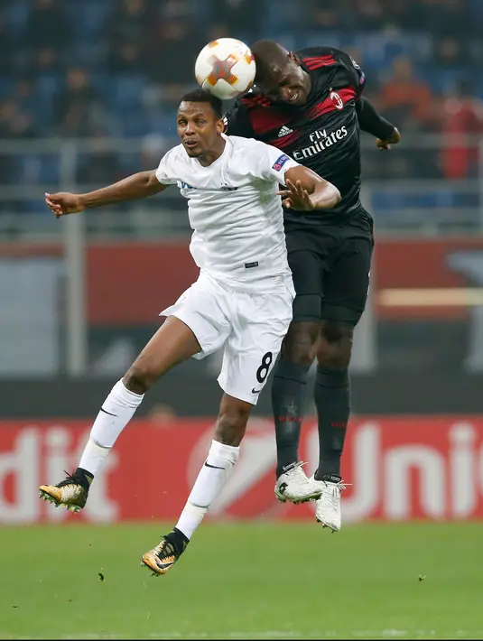 Pemain Austria Wien, Abdullahi Ibrahim Alhassan berebut bola dengan pemain AC Milan, Cristian Zapata pada matchday kelima Liga Europa di Stadion San Siro, Jumat (24/11). Milan lolos ke babak 16 besar usai melumat Austria Wien 5-1. (AP/Antonio Calanni)