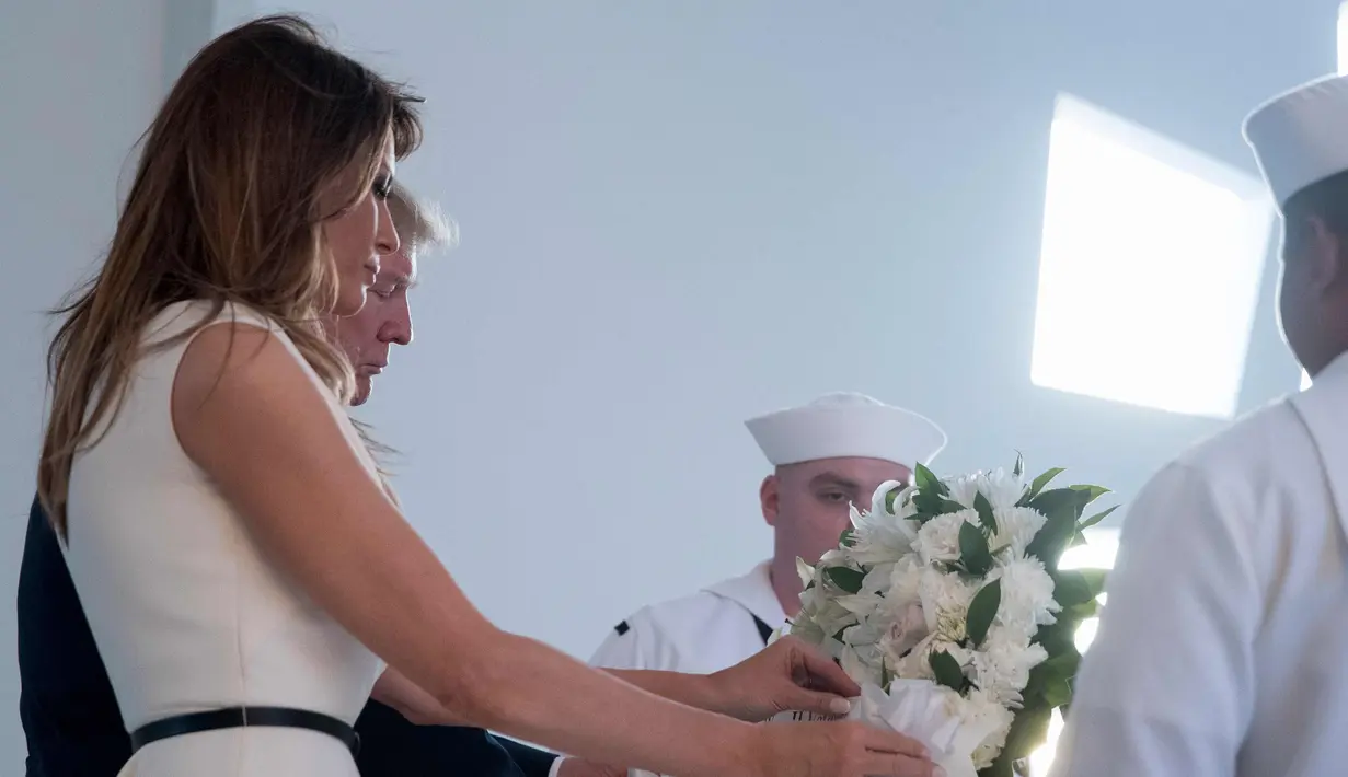Presiden Amerika Serikat, Donald Trump bersama Ibu Negara Melania Trump meletakan karangan bunga saat mengunjungi Pearl Harbor Memorial di Honolulu, Hawaii (3/11). (AP Photo/Andrew Harnik)