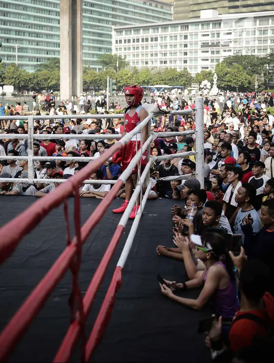 Warga menyaksikan pertandingan tinju amatir yang berlangsung saat Car Free Day di kawasan Bundaran HI, Jakarta, Minggu (29/4). Pertandingan tinju car free day tersebut untuk mendukung penyelenggaraan Asian Games 2018. (Liputan6.com/Faizal Fanani)