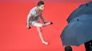 Kristen Stewart melepas sepatunya di karpet merah pemutaran film BlackKkKlansman pada Festival Film Cannes, Prancis, Senin (14/5). Ini merupakan bentuk protes Stewart atas kebijakan panitia yang melarang tamu mengenakan sepatu flat. (AFP/Alberto PIZZOLI)