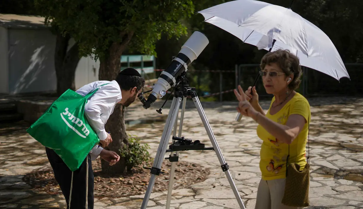 Seorang pria melihat melalui teleskop pada Gerhana Matahari sebagian, saat bulan menutupi sebagian Matahari di kota Givatayim, dekat Tel Aviv, Israel, Selasa (25/10/2022). Peristiwa Gerhana Matahari terakhir pada tahun 2022 terlihat dari sebagian besar Eropa, serta Afrika Utara, Timur Tengah, dan Asia Barat. (AP Photo/Ariel Schalit)