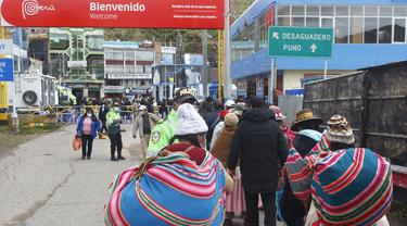 Warga Peru antre memasuki perbatasan Bolivia untuk memasuki negara tersebut, di desa Desaguadero, Peru, pada 18 Februari 2022. Setelah ditutup selama hampir dua tahun karena pandemi Covid-19, Pemerintah Peru mengizinkan pembukaan kembali perbatasan dengan Bolivia dan Ekuador. (Carlos MAMANI/AFP)