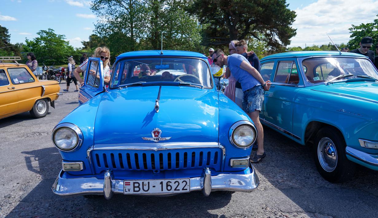 Orang-orang mengamati bagian dalam mobil antik GAZ Volga M21 dalam sebuah festival yang diadakan di Karosta di Kota Liepaja, Latvia, pada 14 Juni 2020. (Xinhua/Janis Laizans)