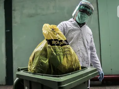Petugas mengenakan APD saat membawa kantong berisi limbah Covid-19 ke Tempat Penyimpanan Sementara Limbah B3 di Laboratorium Kesehatan Daerah (Labkesda) DKI Jakarta, Selasa (4/8/2020). Pembuangan limbah Covid-19 dilakukan dengan proses ketat sesuai protokol kesehatan. (merdeka.com/Iqbal Nugroho)