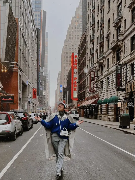 Febby juga mengenakan outfit bermotif dengan sweater biru, dengan inner kemeja putih dan turtleneck. Ia juga mengenakan long coat dan celana abunya. Topi cap dan sling bag mini menjadi pelangkap penampilannya.