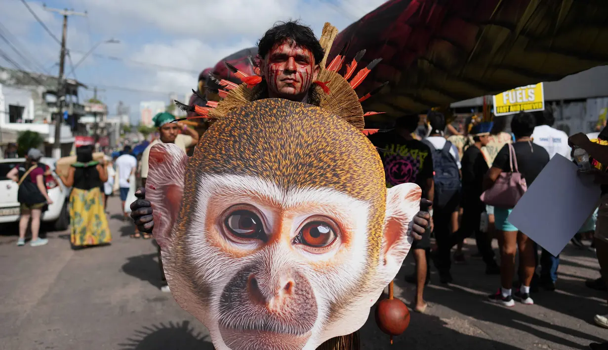 Aksi protes ini juga menggarisbawahi ketegangan antara kebijakan lingkungan pemerintah Brasil dengan realita di lapangan, dimana komunitas adat di Brasil masih menghadapi ancaman dari perluasan agribisnis dan ekstraksi sumber daya. Tampak dalam foto, seorang aktivis asli membawa gambar seekor monyet di tengah-tengah perhelatan Konferensi Tingkat Tinggi Perubahan Iklim PBB (COP30), di Belem, Brasil, Senin 17 November 2025. (AP Photo/Andre Penner)
