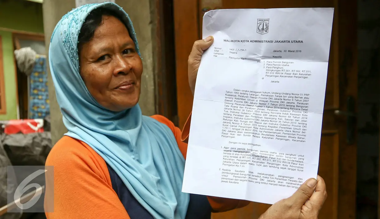 Warga menunjukan surat peringatan (SP1) yang diberikan Wali Kota Jakarta Utara, Rabu (30/3/2016). Sebanyak 310 rumah dan 347 kios di pasar ikan penjaringan akan dibongkar pihak Pemprov DKI. (Liputan6.com/Yoppy Renato)