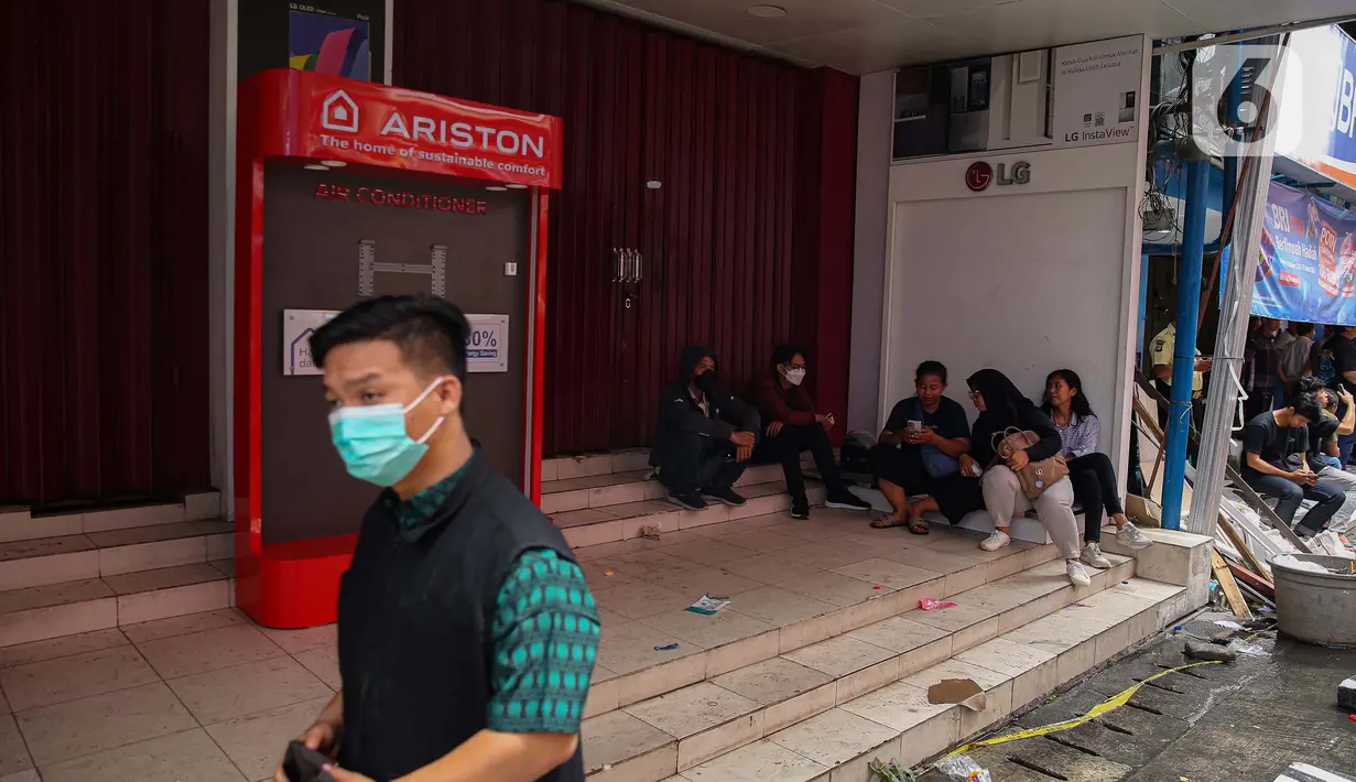 Beberapa orang terlihat duduk di depan sejumlah toko dan perkantoran yang tutup di sekitar kompleks dengan Glodok Plaza, Jakarta, Kamis (16/1/2025). (Liputan6.com/Angga Yuniar)