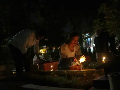Warga keturunan Portugis menyalakan lilin saat melakukan ziarah ke makam anggota keluarga mereka pada malam Natal di kompleks Gereja Protestan Indonesia Barat (GPIB) Tugu, Semper Barat, Cilincing, Jakarta Utara, Minggu (24/12/2023). Ziarah tersebut menjadi tradisi keluarga keturunan Portugis di Kampung Tugu menjelang Hari Raya Natal. (Liputan6.com/Herman Zakharia)