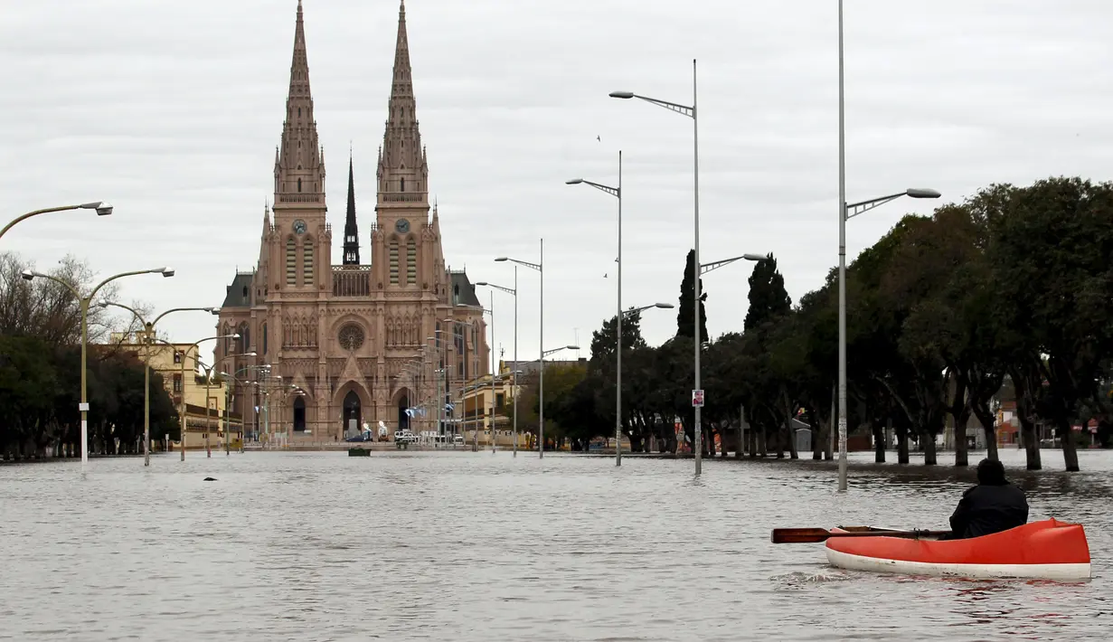 Warga menggunakan perahu saat melihat kondisi banjir di depan Basilika Lujan, Argentina, Rabu (12/8/2015). Lebih dari 20.000 orang telah dievakuasi setelah hujan lebat di akhir pekan lalu yang menyebabkan sungai naik dan banjir. (REUTERS/Marcos Brindicci)