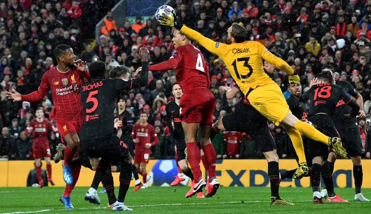 Kiper Atletico Madrid, Jan Oblak berusaha menipis bola sundulan bek Liverpool Virgil van Dijk pada kedua 16 besar Liga Champions di Anfield, Inggris (11/3/2020). Oblak melakukan sembilan penyelamatan dipertandingan ini dan membawa atletico ke perempat final. (AFP/Paul Ellis)