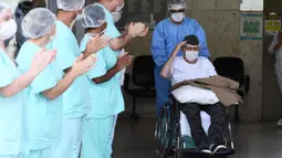 Veteran Perang Dunia II asal Brasil, Ermando Armelino Piveta meninggalkan Rumah Sakit Angkatan Bersenjata setelah pulih dari covid-19 di Brasilia, Selasa (14/4/2020). Kakek berusia 99 tahun itu dinyatakan sembuh dari virus Corona setelah dirawat selama delapan hari. (EVARISTO SA/AFP)