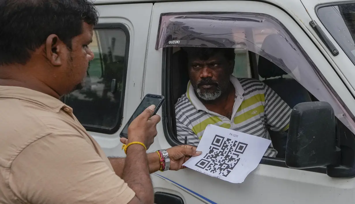 Seorang pekerja memindai kode QR sebelum mengisi bensin ke kendaraan di sebuah pompa bensin di Kolombo, Sri Lanka, Senin, 1 Agustus 2022. Sri Lanka memperkenalkan distribusi bahan bakar menggunakan kode QR pada hari Senin sebagai bagian dari penerapan kuota mingguan untuk pengendara. (AP Photo/Eranga Jayawardena)