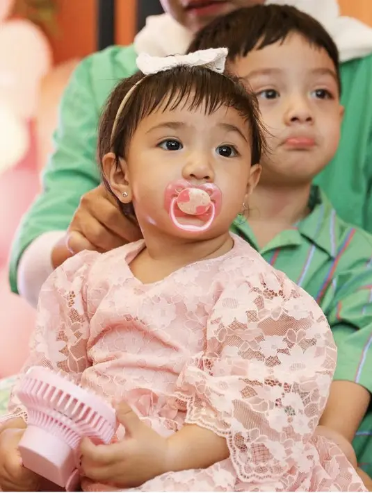 Amala menggemaskan dengan menggunakan empang di mulut sambil memegang kipas pink di tangannya. [@_irishbella_]
