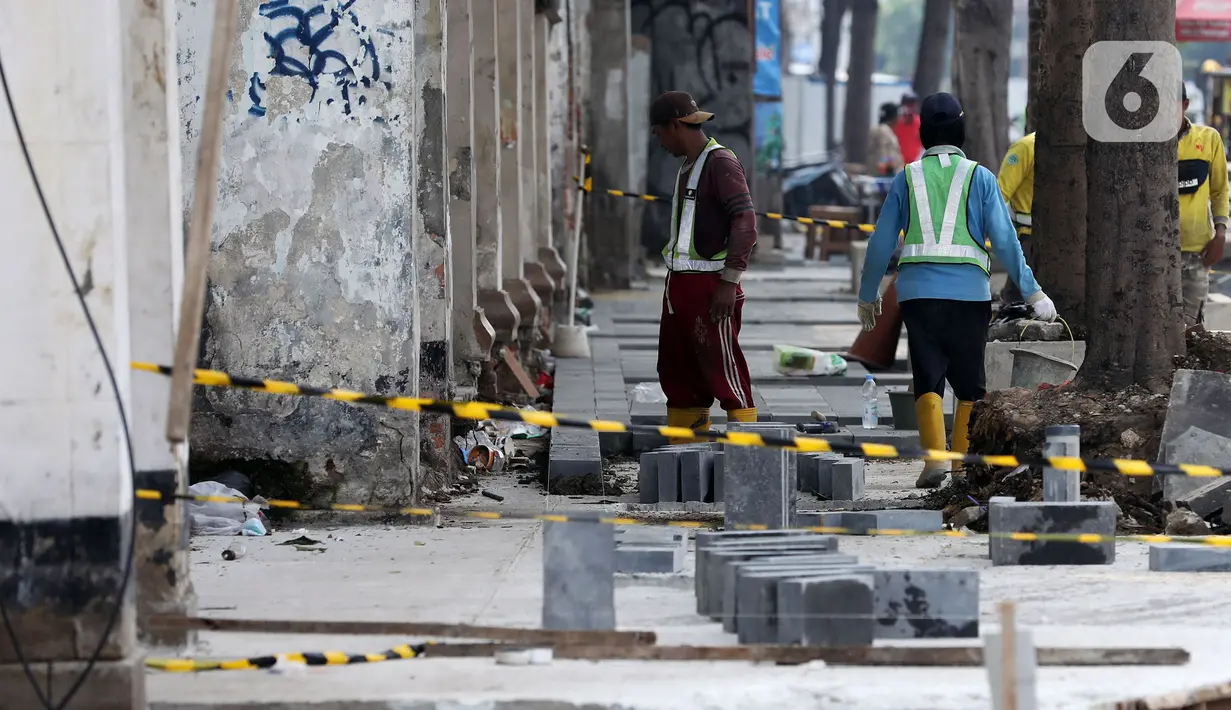 Pekerja mengerjakan proyek rivitalisasi jalan di kawasan Kota Tua, Jakarta Barat, Senin (17/5/2022). Revitalisasi difokuskan bagian Trotoar yang nantinya akan diperlebar menjadi tiga meter sehingga cukup luas untuk para pejalan kaki. Dan juga akan dilengkapi dengan ubin pengarah (guidingblock) serta jalur khusus sepeda. (Liputan6.com/Johan Tallo)