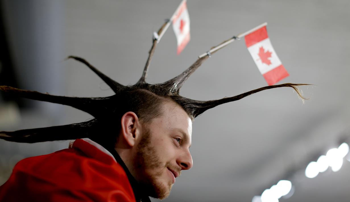 Seorang pria menata rambutnya dengan unik saat menyaksikan cabang curling antara Rusia dan Swiss pada Olimpiade Musim Dingin 2018 di Gangneung, Korea Selatan, Senin (12/2). Ada 92 negara peserta yang mengikuti ajang tersebut. (AP/Natacha Pisarenko)