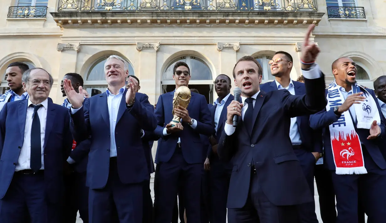 Presiden Emmanuel Macron menyampaikan sambutan di samping pelatih timnas Prancis, Didier Deschamps pada penyambutan tim sepakbola negaranya yang menjadi juara Piala Dunia 2018 di Istana Kepresidenan Elysee, Paris, Senin (16/7). (Ludovic Marin/Pool via AP)
