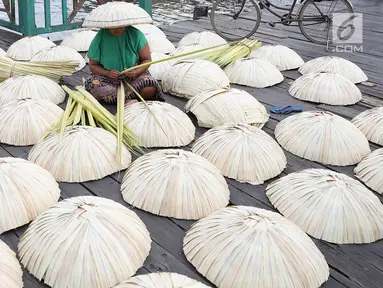 Perajin membuat caping khas Banjar di kawasan Pasar Apung Kuin, Kalimantan Selatan, Senin (26/3). Caping yang disebut tanggui oleh masyarakat Banjar tersebut merupakan topi tradisional khas Banjar. (Liputan6.com/Immanuel Antonius)