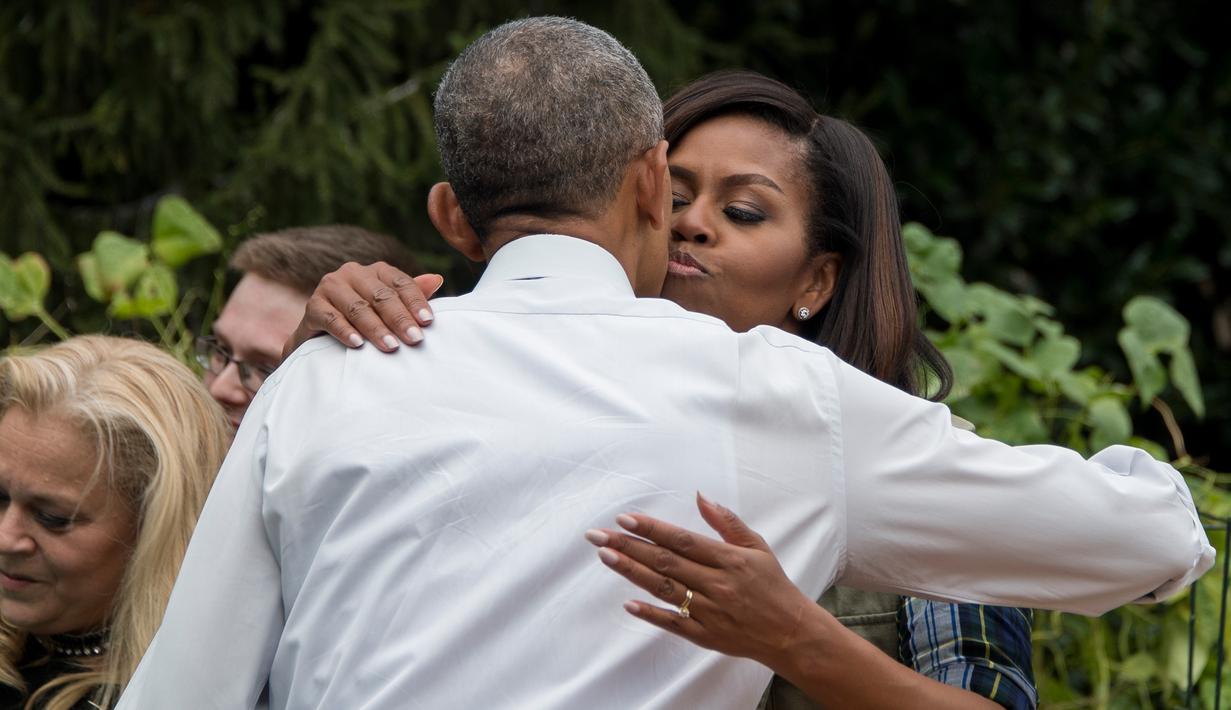 Ibu negara AS Michelle Obama berpelukan dengan sang suami Presiden AS, Barack Obama saat memanen ubi jalar di kebun Gedung Putih, Washington, (6/10). (AFP Photo/Jim Watson)