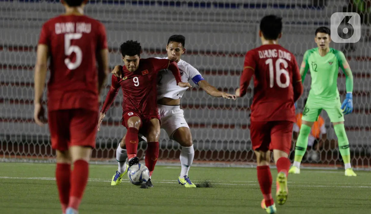 Bek Timnas Indonesia U-22, Andy Setyo, berebut bola dengan striker Vietnam U-22, Ha Duc Chinh, pada laga SEA Games 2019 di Stadion Rizal Memorial, Manila, Filipina, Minggu (1/12/2019). Indonesia kalah 1-2 dari Vietnam. (Bola.com/M Iqbal Ichsan)