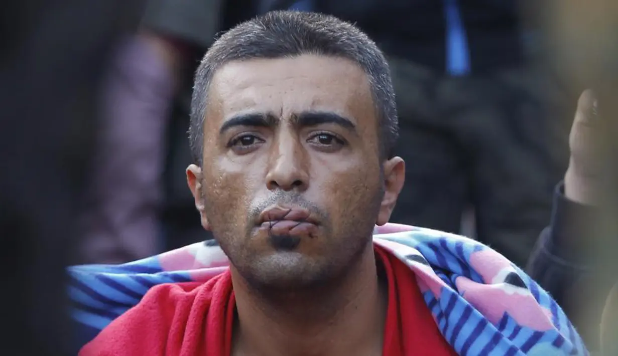 Seorang imigran menjahit mulutnya sebagai aksi protes di perbatasan  Yunani dekat desa Gevgelija, Makedonia (23/11/2015). (REUTERS / Ognen Teofilovski)