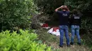 Peneliti melihat sisa-sisa manusia, yang ditempatkan di tas merah, digali dari situs kuburan massal rahasia di Arbolillo, negara bagian Veracruz, Meksiko, Jumat (7/9). Satu hari sebelumnya pihak berwenang menemukan 166 tengkorak manusia (AP/Felix Marquez)