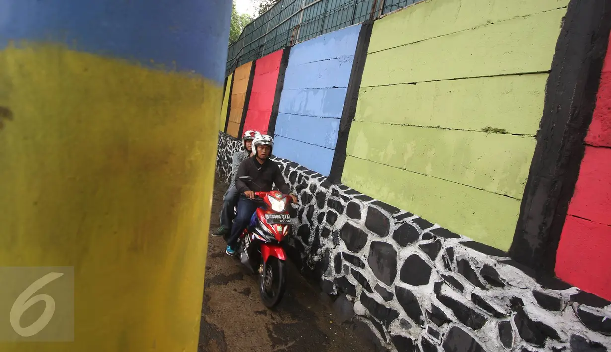 Pengendara melintas dekat tembok warna-warni di Kampung Penas Tanggul, Cipinang Besar Selatan, Jakarta, Kamis (23/3). Kampung warna-warni tanpa rokok itu dibuat warga sebagai upaya perlindungan bagi perempuan dan anak. (Liputan6.com/Immanuel Antonius)