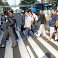 Warga melintasi Pelican Crossing di sekitar Halte Transjakarta Gelora Bung Karno, Jakarta, Jumat, (30/11). Ada tiga jembatan penyeberangan orang (JPO) di Jalan Jenderal Sudirman, Jakarta, yang sedang direvitalisasi. (Liputan6.com/Helmi Fithriansyah)