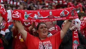 Seorang penggemar Liverpool mengangkat syal yang didedikasikan untuk mendiang Diogo Jota, menjelang pertandingan persahabatan pramusim pertama antara Liverpool dan Athletic Bilbao di Anfield, Liverpool, Senin (4/8/ 2025) dini hari WIB. (Darren Staples / AFP)