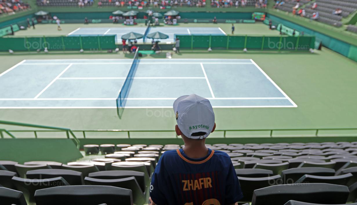 Suporter cilik Zhafir serius menyaksikan laga David Agung Susanto melawan petenis Filipina, Jeson Patrombon pada Piala Davis 2018 grup dua Asia/Oceania di Senayan, Jakarta, Sabtu (3/2/2018). David menang 6-2, 7-5. (Bola.com/Nick Hanoatubun)