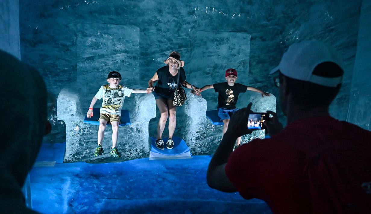 Wisatawan berpose saat mengunjungi gua es yang dikenal dengan "La Grotte de Glace", di gletser Mer de Glace (Lautan Es) di Chamonix-Mont-Blanc, Pegunungan Alpen Prancis, Jumat (19/7/2019). Gua di lereng Mont Blanc ini memiliki panjang 7 km dengan kedalaman 200 meter. (PHILIPPE DESMAZES/AFP)