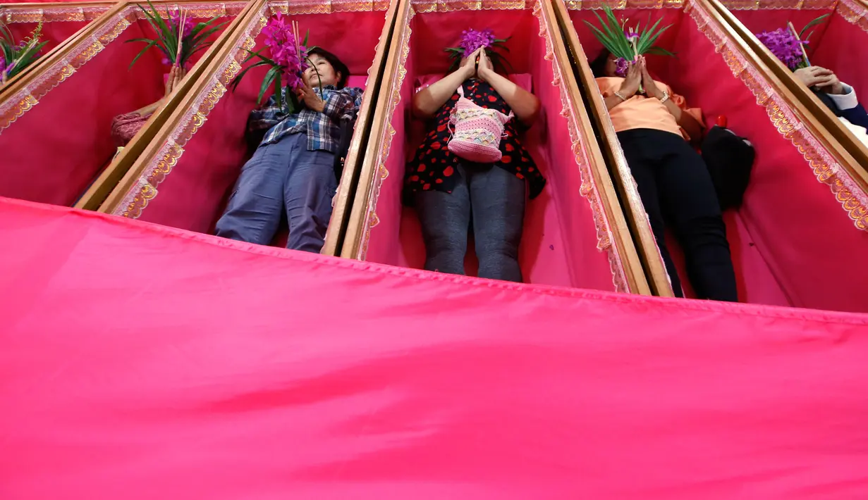 Sejumlah pemuja berdoa saat mereka berbaring dalam peti mati di kuil Takien, pinggiran kota Bangkok, Thailand, Senin (31/12). Upacara agama ini sebagai bagian dari ritual untuk menerima kematian yang tidak bisa dihindari manusia. (AP/Sakchai lalit)