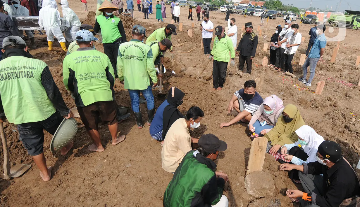Keluarga korban Covid-19 berdoa usai penguburan di TPU Rorotan, Jakarta Utara, Senin (28/06/20121). Sudah lebih dari dua pekan petugas kewalahan memakamkan korban covid-19, dimana dalam seharinya mereka memakamkan rata-rata 110 jenazah dari pagi hingga pukul 23.00. (merdelka.com/Arie Basuki)