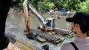 Pekerja menggunakan alat berat untuk mengeruk lumpur dan sampah yang mengendap di anak Sungai Ciliwung, Jakarta, Jumat (26/1). (Liputan6.com/Immanuel Antonius)