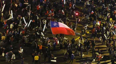 Seorang Suporter membawa bendera nasional Chile di kerumunan merayakan kemenangan Chile atas Uruguay di Copa America 2015 di Santiago, Chile, (25/6/2015). Chile melaju ke semifinal usai mengalahkan Uruguay 1-0. (REUTERS/Catherine Allen)