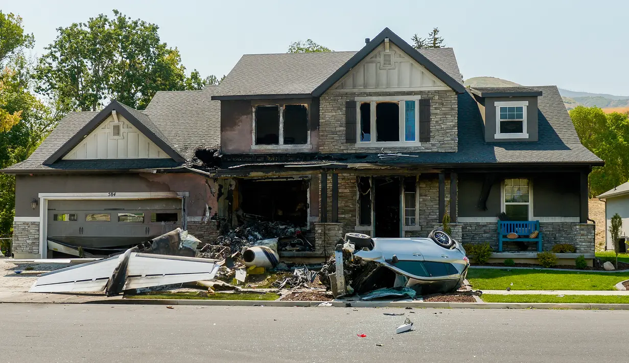 Kondisi sebuah rumah yang sengaja ditabrak oleh pesawat kecil di Payson, Utah, AS, Senin (13/8). Pesawat berwarna putih itu hangus terbakar dan hancur di halaman rumah, dekat sebuah mobil yang terguling. (Leah Hogsten/The Salt Lake Tribune via AP)