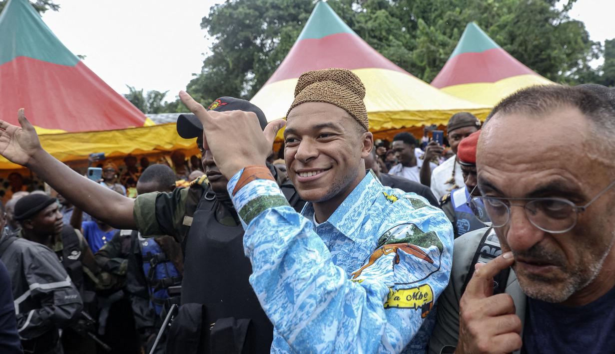 Pemain Paris Saint-Germain dan kapten Timnas Prancis, Kylian Mbappe (tengah) mengenakan pakaian tradisional saat mengunjungi desa ayahnya, Wilfrid Mbappe, di Djebale, Kamerun pada 8 Juli 2023. (AFP/Daniel Beloumou Olomo)