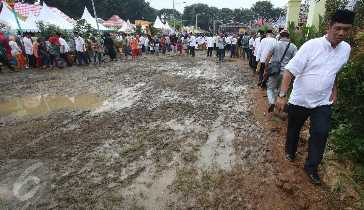 Pengunjung menghindari jalan yang becek pada Festival Lebaran Betawi IX, Jakarta, (14/8). Festival diramaikan dengan rumah adat Betawi dari masing-masing pemkot  administrasi Jakarta serta Kabupaten Kepulauan Seribu. (Liputan6.com/Immanuel Antonius)