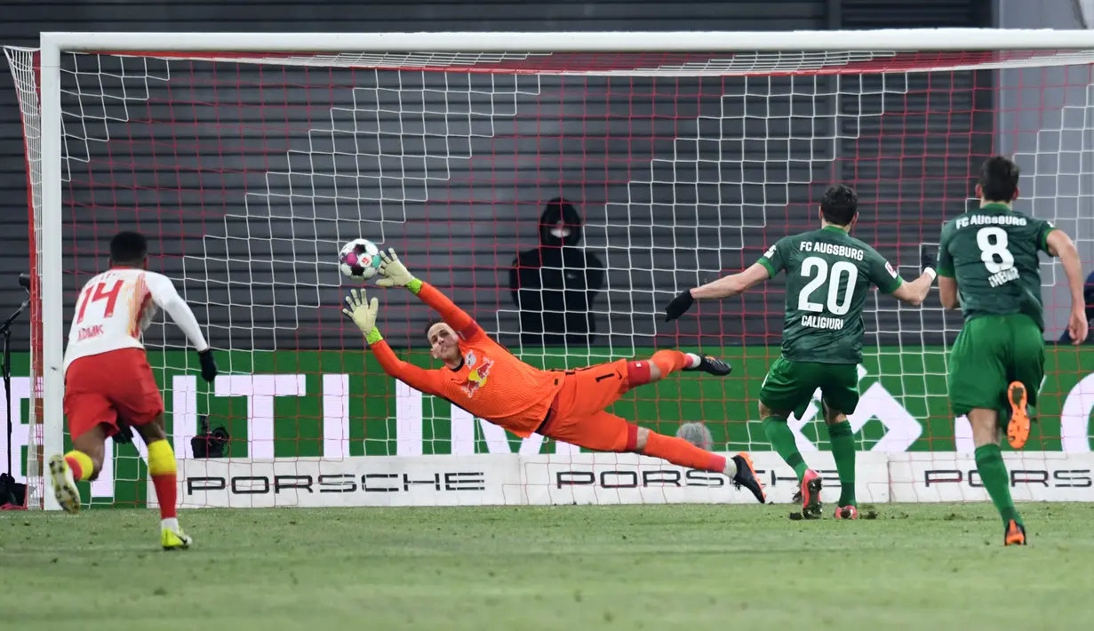 Aksi ciamik juga ditunjukkan oleh kiper RB Leipzig, Peter Gulacsi tapi sayangnya bola tendangan dari pemain Augsburg Daniel Caligiuri tidak bisa dibendung olehnya. (Foto: AFP/Pool/Annegret Hilse)