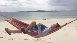 Pemeran Bambang di Diam-Diam Suka ini menikmati pantai White Sand Island di Riau. Sambil tertidur di hammock, pria yang akrab disapa Rangga ini menikmati suasana pantai. (Liputan6.com/IG/@azofrangga)
