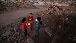 Kehangatan suasana jelang buan suci Ramadan begitu terasa di tengah hamparan tenda pengungsi dan kondisi yang serba terbatas. Tampak dalam foto, beberapa pengungsi muda Palestina bermain di reruntuhan bangunan yang hancur di kamp pengungsi Bureij di Jalur Gaza tengah pada 15 Februari 2026. (Eyad Baba/AFP)