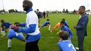 Pemain Timnas Prancis, Patrice Evra, memberi pengarahan kepada para pemain muda Les Ulis saat latihan ringan sebelum bertanding, (23/5/2016). (AFP/Franck Fife) 