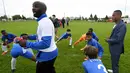 Pemain Timnas Prancis, Patrice Evra, memberi pengarahan kepada para pemain muda Les Ulis saat latihan ringan sebelum bertanding, (23/5/2016). (AFP/Franck Fife) 