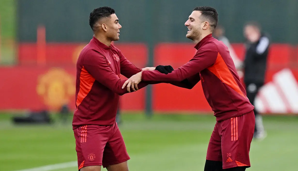 Pemain Manchester United, Casemiro dan Diogo Dalot, tampak bercanda saat sesi latihan di Carrington Training Complex, Senin (23/10/2023). (AFP/Paul Ellis)