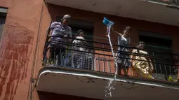 Orang-orang saling melempar air saat perang air tahunan di jalan-jalan lingkungan Vallecas, Madrid, Spanyol, 17 Juli 2022. Para tetangga yang berada di balkon mereka tak henti-hentinya melemparkan air untuk mengisi ember air orang-orang yang lewat. (AP Photo/Manu Fernandez)