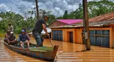 Orang-orang menaiki rakit di daerah yang terendam banjir setelah Sungai Acre meluap di Cobija, Bolivia, pada tanggal 29 Februari 2024. (STRINGER/AFP)